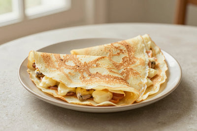 Folded basic french crêpes on a plate, the filling and toppings from the recipe clearly visible