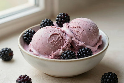 Two generous scoops of blackberry ice cream in a shallow ceramic bowl, softly melting at the edges