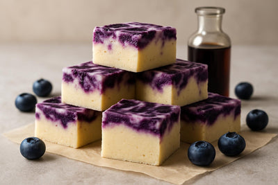 Squares of blueberry cheesecake fudge on parchment