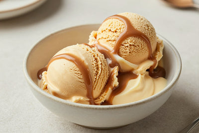 Two generous scoops of butterscotch ice cream in a shallow ceramic bowl, softly melting at the edges