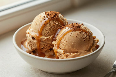 Two generous scoops of caramel coffee ice cream in a shallow ceramic bowl, softly melting at the edges