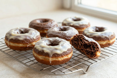 Fresh chocolate cake doughnuts on a wire cooling rack, one broken open to show the tender inside