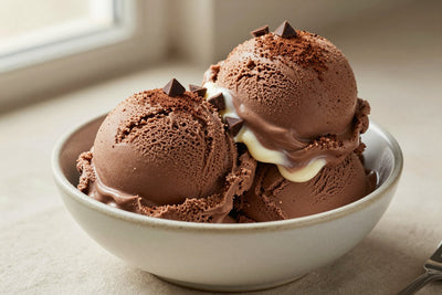 Two generous scoops of chocolate cheesecake ice cream in a shallow ceramic bowl, softly melting at the edges