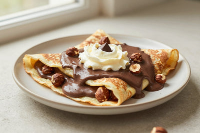 Folded chocolate hazelnut crêpes on a plate, the filling and toppings from the recipe clearly visible
