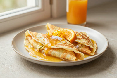 Folded crêpes suzette on a plate, the filling and toppings from the recipe clearly visible