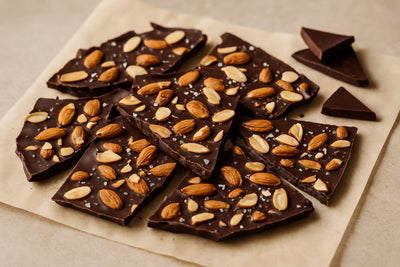 Shards of dark chocolate almond bark on parchment