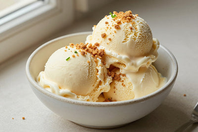 Two generous scoops of key lime pie ice cream in a shallow ceramic bowl, softly melting at the edges