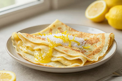 Folded lemon sugar crêpes on a plate, the filling and toppings from the recipe clearly visible