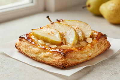 Pear frangipane puff pastry on parchment, showing crisp, flaky, deep golden layers