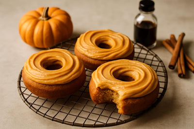 Doughnuts finished with pumpkin cream cheese frosting on a cooling rack