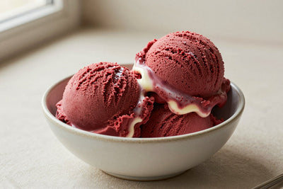 Two generous scoops of red velvet ice cream in a shallow ceramic bowl, softly melting at the edges