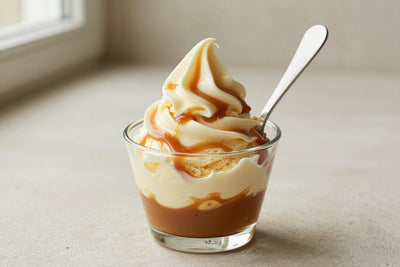 A generous swirl of salted caramel gelato in a small glass cup with a flat gelato spade