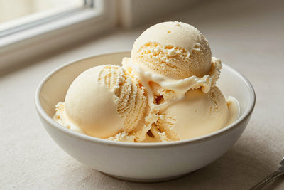 Two generous scoops of vanilla bean ice cream in a shallow ceramic bowl, softly melting at the edges