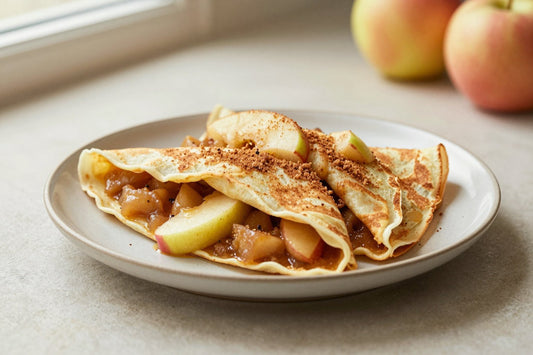 Folded apple cinnamon crêpes on a plate, the filling and toppings from the recipe clearly visible