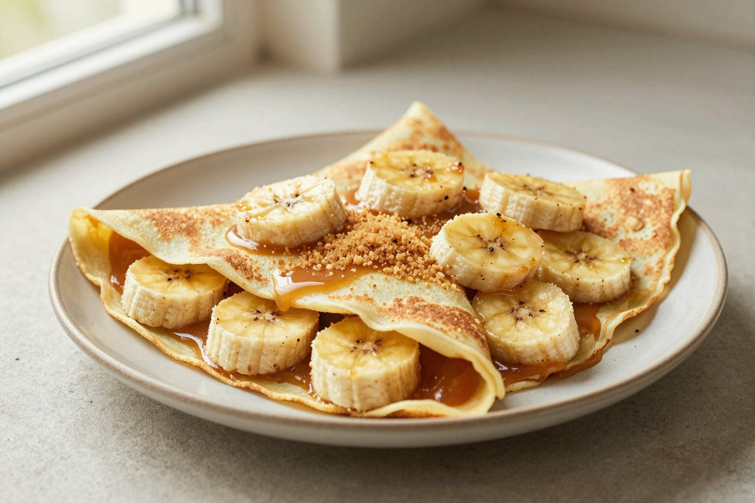 Folded banana crêpes on a plate, the filling and toppings from the recipe clearly visible