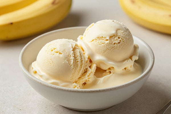 Two generous scoops of banana ice cream in a shallow ceramic bowl, softly melting at the edges
