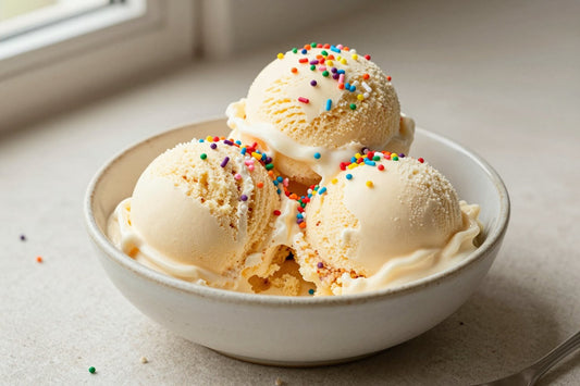 Two generous scoops of birthday cake ice cream in a shallow ceramic bowl, softly melting at the edges