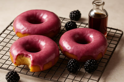 Doughnuts finished with blackberry glaze on a cooling rack