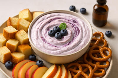 Bowl of blueberry cheesecake dip with brioche, pretzels and fruit