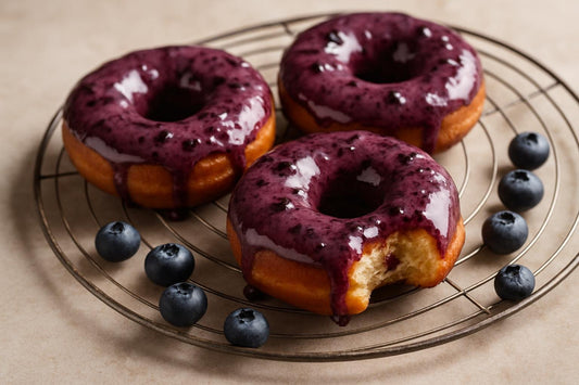 Doughnuts finished with blueberry sauce on a cooling rack
