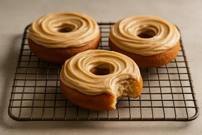 Doughnuts finished with brown butter frosting on a cooling rack