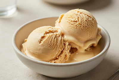 Two generous scoops of brown butter ice cream in a shallow ceramic bowl, softly melting at the edges