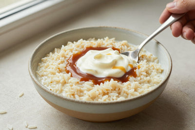 Creamy caramel rice pudding in a small ceramic bowl with a spoon, garnished as in the recipe