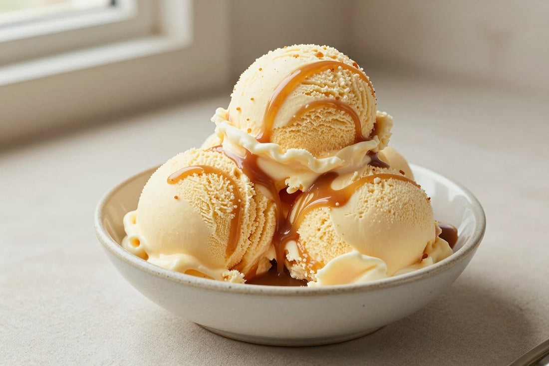 Two generous scoops of caramel swirl ice cream in a shallow ceramic bowl, softly melting at the edges