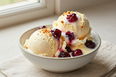 Two generous scoops of cherry cheesecake ice cream in a shallow ceramic bowl, softly melting at the edges