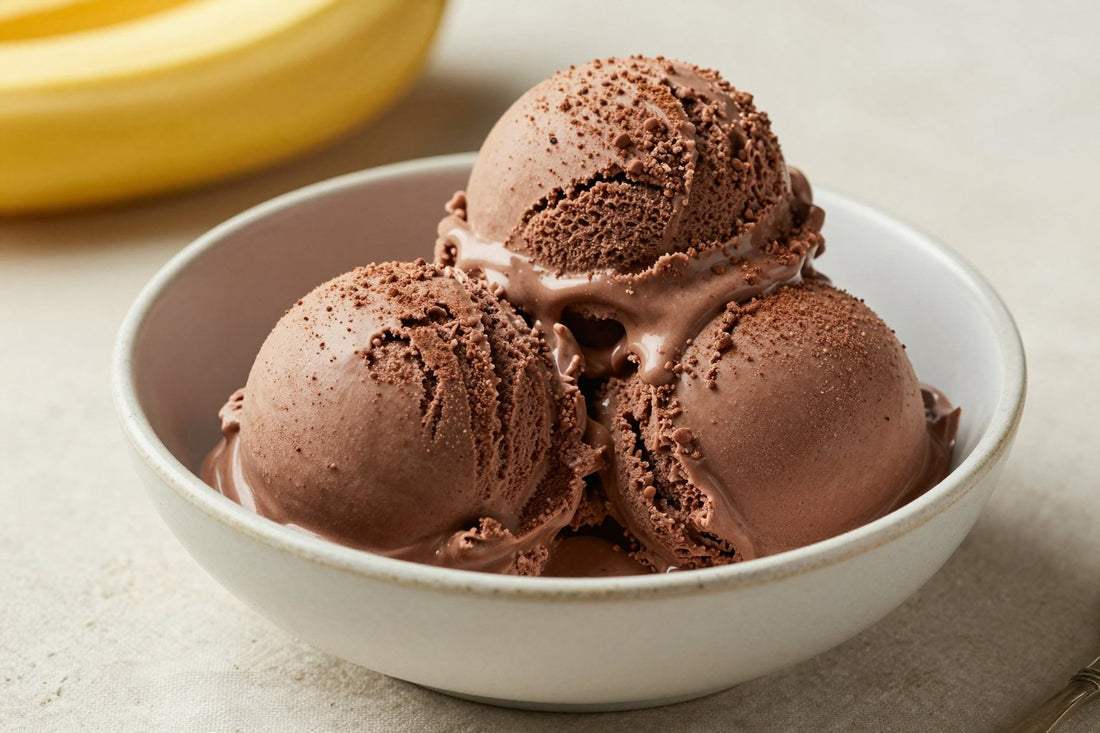 Two generous scoops of chocolate banana ice cream in a shallow ceramic bowl, softly melting at the edges