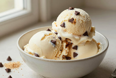 Two generous scoops of chocolate chip cookie dough ice cream in a shallow ceramic bowl, softly melting at the edges
