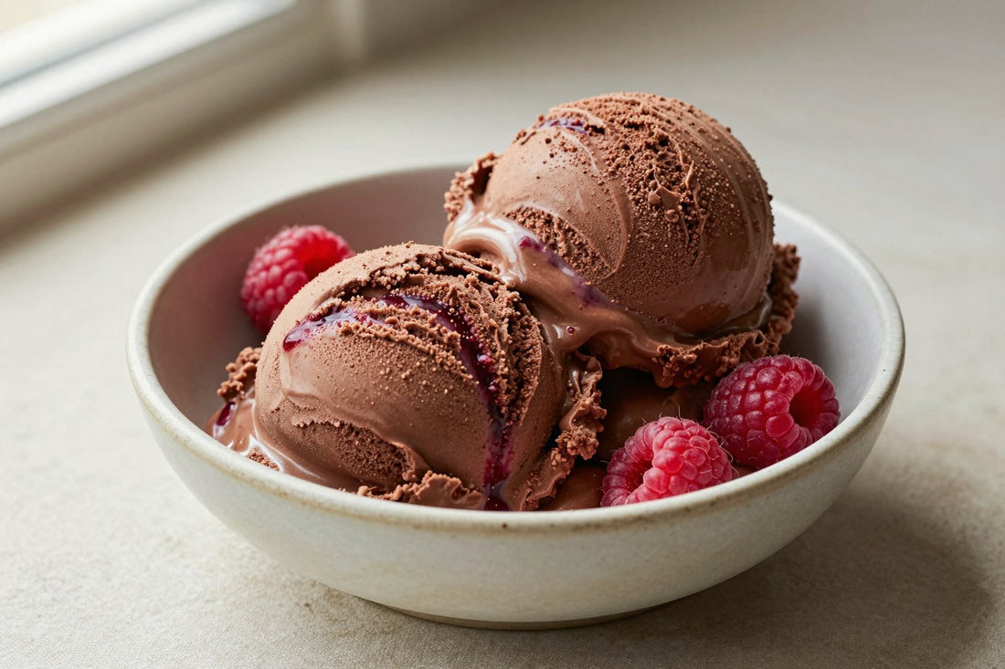 Two generous scoops of chocolate raspberry ice cream in a shallow ceramic bowl, softly melting at the edges