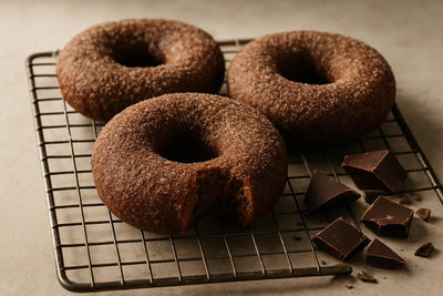 Doughnuts finished with chocolate sugar dusting on a cooling rack