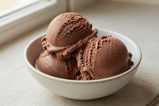 Two generous scoops of classic chocolate ice cream in a shallow ceramic bowl, softly melting at the edges