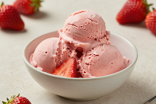 Two generous scoops of classic strawberry ice cream in a shallow ceramic bowl, softly melting at the edges