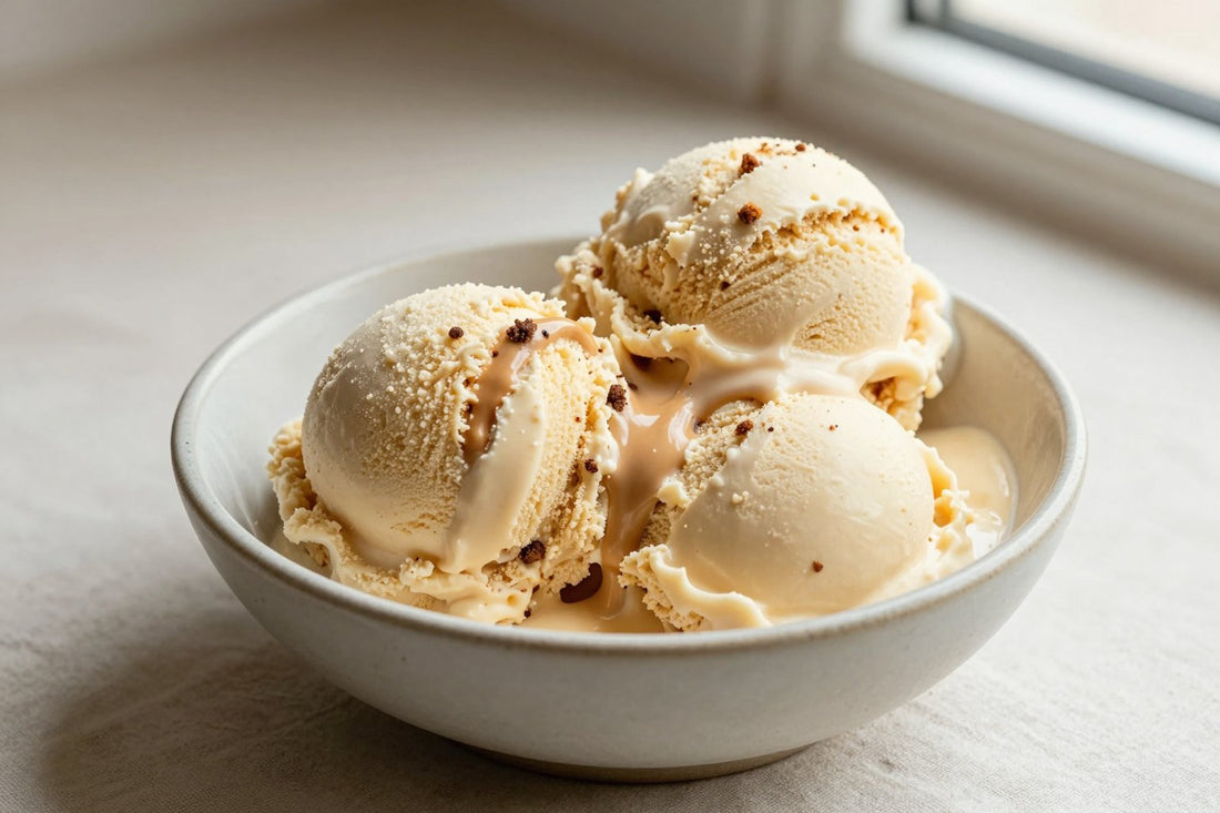 Two generous scoops of cookie butter ice cream in a shallow ceramic bowl, softly melting at the edges