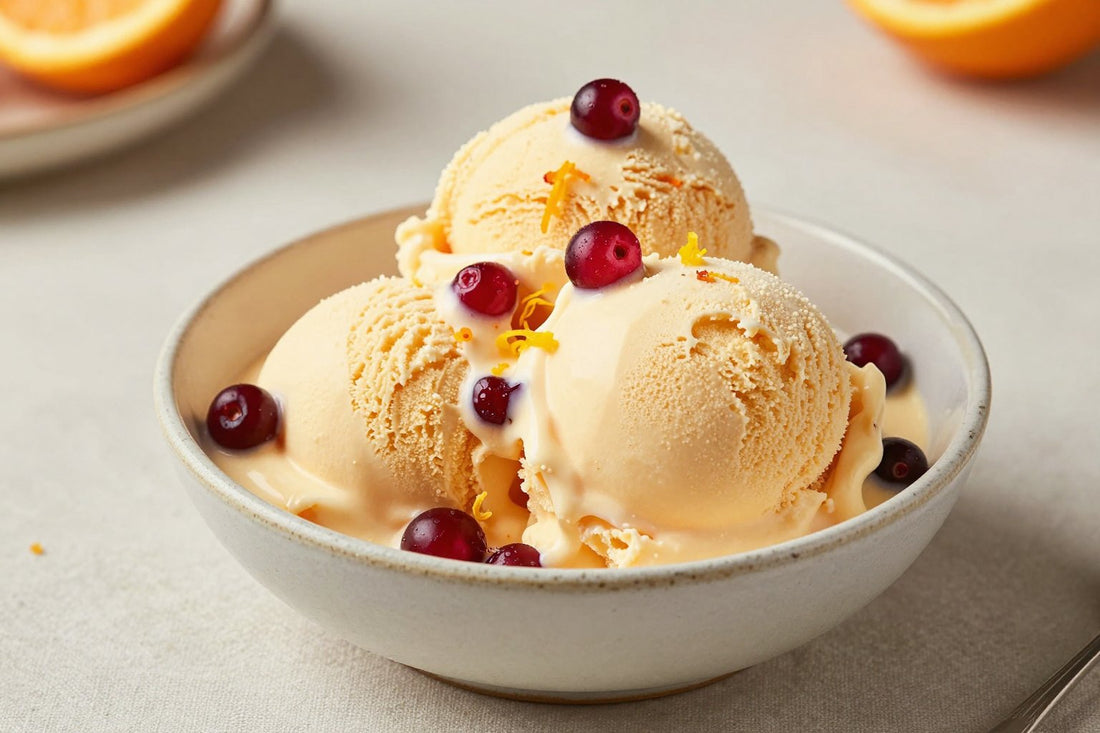 Two generous scoops of cranberry orange ice cream in a shallow ceramic bowl, softly melting at the edges