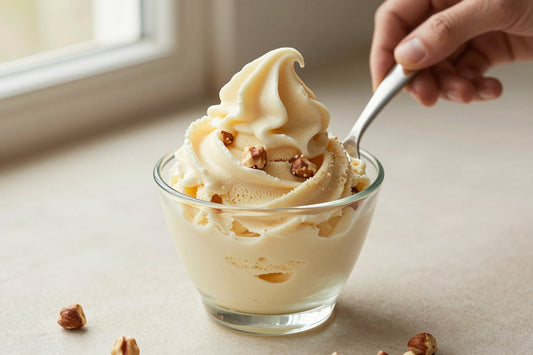 A generous swirl of hazelnut gelato in a small glass cup with a flat gelato spade