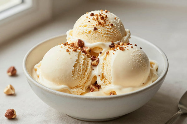 Two generous scoops of hazelnut ice cream in a shallow ceramic bowl, softly melting at the edges