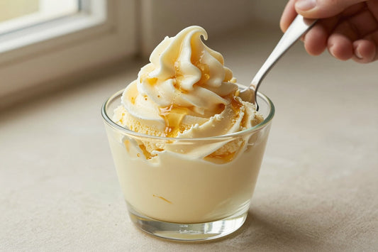 A generous swirl of honey gelato in a small glass cup with a flat gelato spade