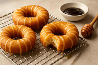 Doughnuts finished with honey vanilla drizzle on a cooling rack