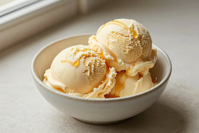 Two generous scoops of honey vanilla ice cream in a shallow ceramic bowl, softly melting at the edges