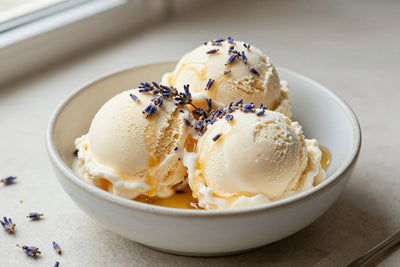 Two generous scoops of lavender honey ice cream in a shallow ceramic bowl, softly melting at the edges