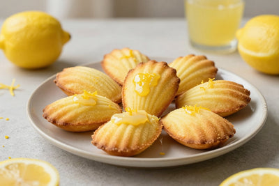 Shell-shaped lemon madeleines on a plate, showing their golden humps and ridged sides