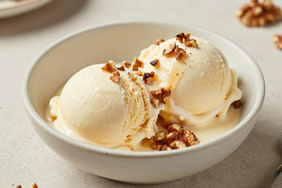 Two generous scoops of maple walnut ice cream in a shallow ceramic bowl, softly melting at the edges