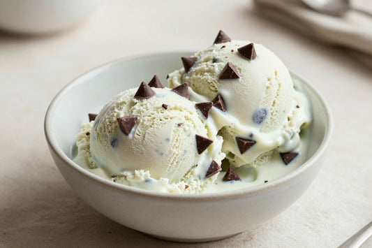 Two generous scoops of mint chocolate chip ice cream in a shallow ceramic bowl, softly melting at the edges