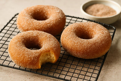Doughnuts finished with nutmeg sugar on a cooling rack