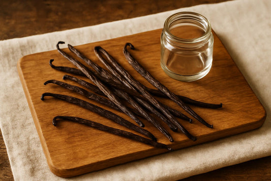 Whole Madagascar vanilla beans scattered on a wooden cutting board beside a small glass jar, shot from above with natural