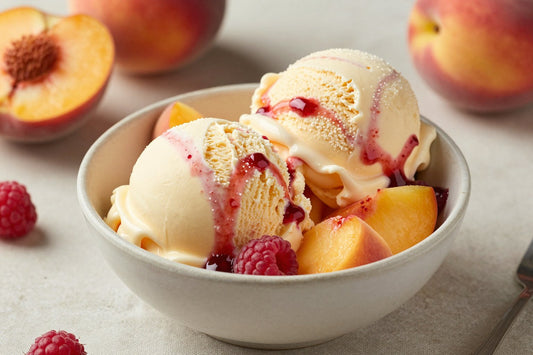 Two generous scoops of peach melba ice cream in a shallow ceramic bowl, softly melting at the edges