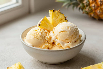 Two generous scoops of pineapple ice cream in a shallow ceramic bowl, softly melting at the edges